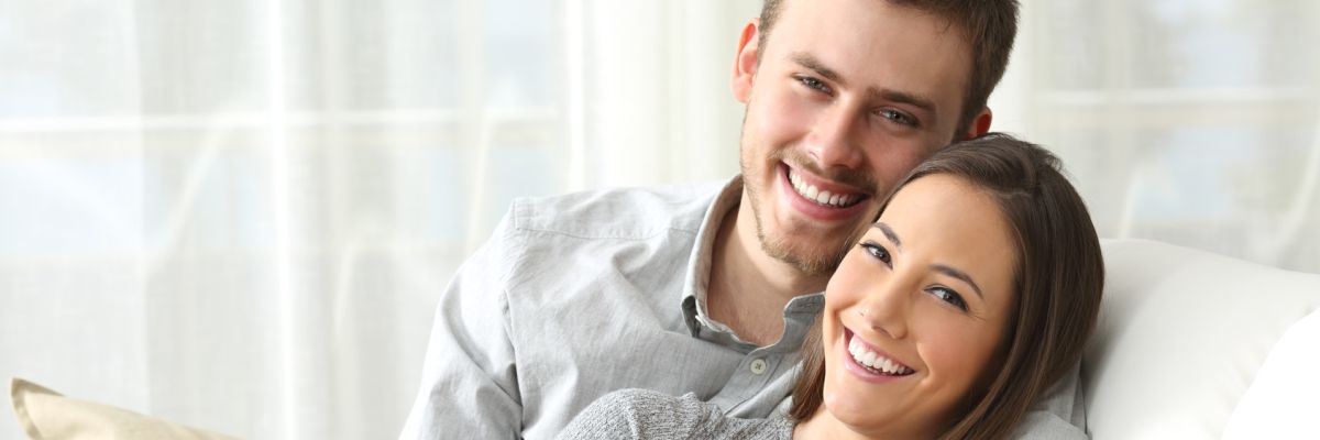Happy couple looking to camera at home